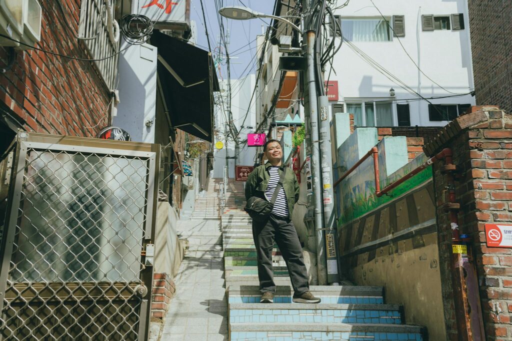 A man standing on a colorful staircase in a vibrant Seoul alley, showcasing local architecture.