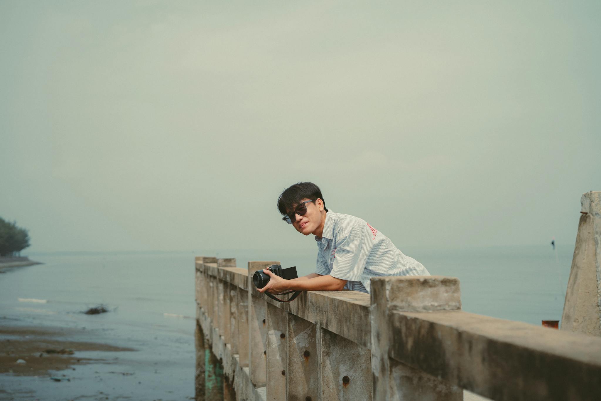 A man with a camera leans on a pier in Ho Chi Minh City, Vietnam.