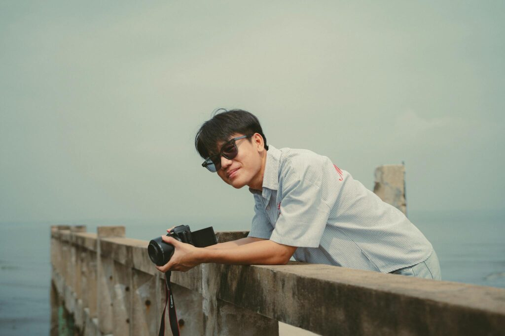 Young man with camera at a pier in Ho Chi Minh City, enjoying the view and capturing memories.