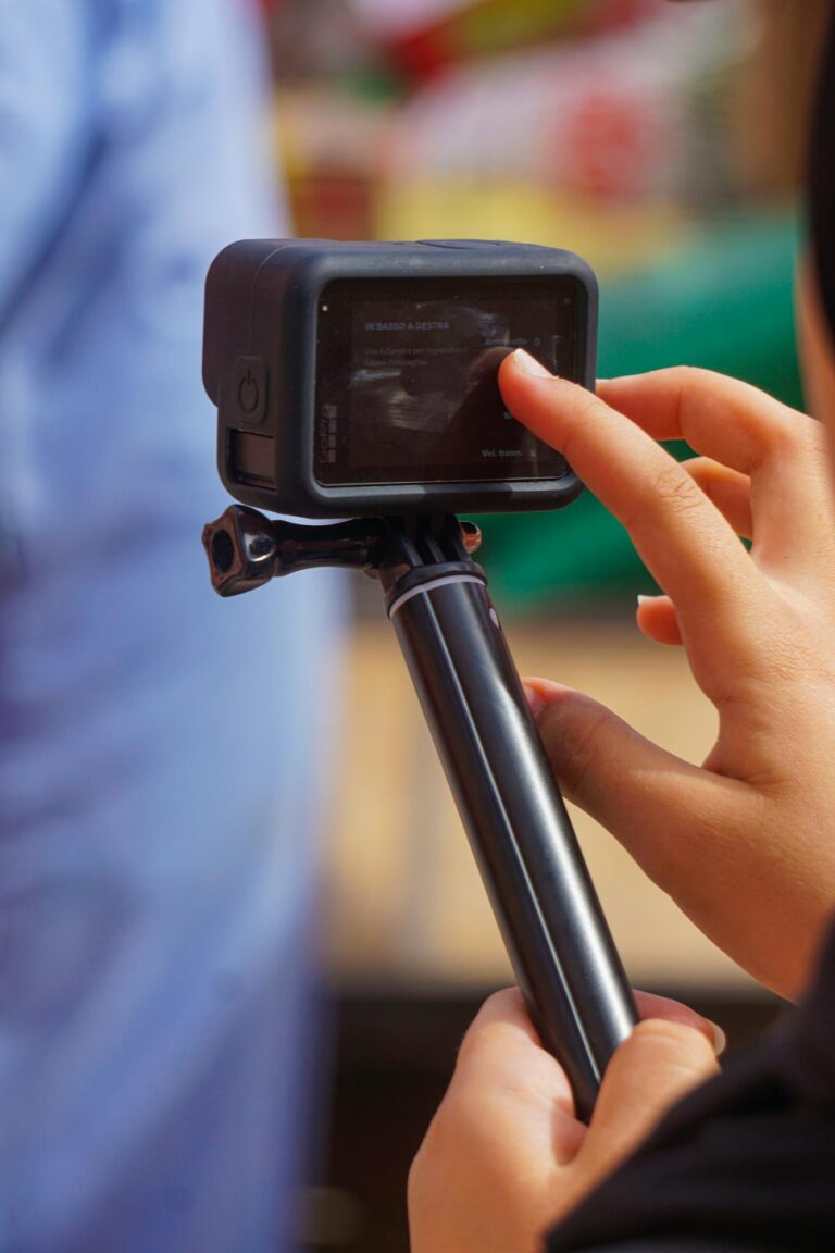 Close-up of a person's hand operating an action camera with a touchscreen mounted on a tripod.
