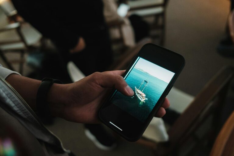 Hand holding a smartphone displaying a yacht photo, perfect travel inspiration.